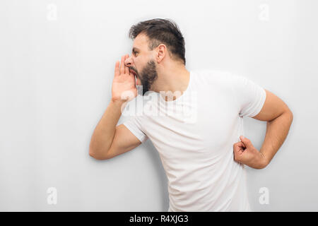 Emotional Man che esprime i suoi sentimenti. Egli grida e urla. Guy coveres la bocca con la mano da un lato. Isolato su sfondo bianco. Foto Stock