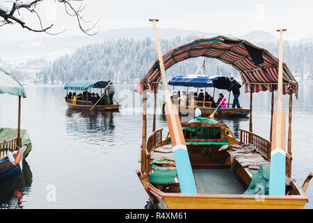 BLED, SLOVENIA - Gennaio 2015: piccoli battellieri il trasporto dei turisti per l'isola del lago. Barche a vuoto sul primo piano. Foto Stock