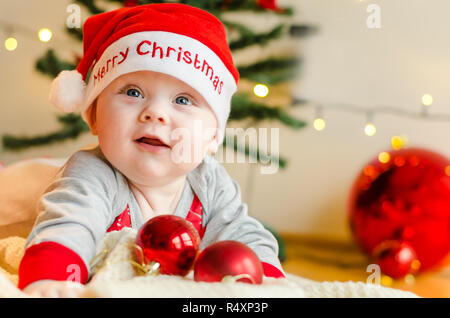 Felice Natale baby boy intorno all albero di Natale e decorazioni in attesa del Natale Foto Stock