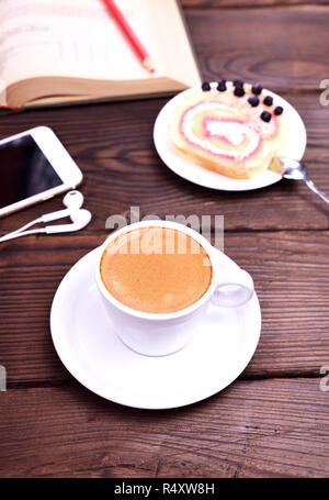 Tazza di caffè e un telefono cellulare su una tabella di colore marrone Foto Stock