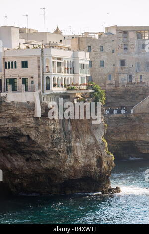 Case tradizionali su scogliere a picco sul mare con grotte che salgono dal mare Adriatico a Polignano a Mare, Italia, soleggiata giornata estiva Foto Stock