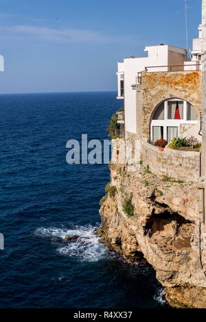 Case tradizionali su scogliere a picco sul mare con grotte che salgono dal mare Adriatico a Polignano a Mare, Italia, soleggiata giornata estiva Foto Stock