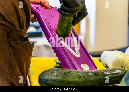 Lo Chef maschio Tagliare le melanzane in cucina - con guanto sulla mano Foto Stock