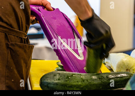 Lo Chef maschio Tagliare le melanzane in cucina - con guanto sulla mano Foto Stock