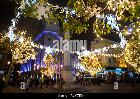 Scenic vista notturna di scintillanti luci di Natale infilate attraverso gli alberi che circondano il centro storico di Seven Dials monumento in London, England, Regno Unito Foto Stock