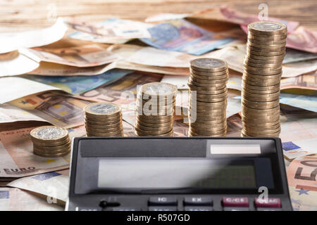 Calcolatrice con moneta impilati e moneta note Foto Stock