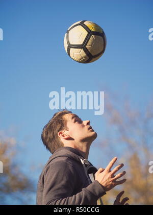 Giocatore di calcio a fare pratica con il calcio nel parco su una soleggiata giornata autunnale Foto Stock