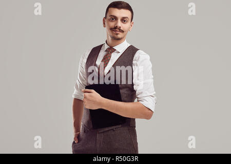 Ritratto di bel giovane fiducioso arabo imprenditore con baffi di fantasia in lana abito marrone su sfondo per studio Foto Stock
