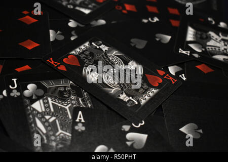 Scatto sorprendente di bianco e nero giocando a carte con il Re di Cuori in appoggio sulla sommità della pila. Accenni di rosso aggiungere enfasi al simbolo del cuore. Foto Stock