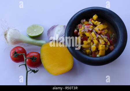 Salsa di mango in un recipiente in pietra con ingredienti in background Foto Stock