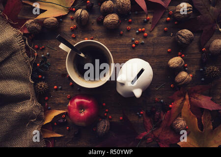 Salvadanaio di banca di monete con decorazione in autunno la disposizione sul tavolo di legno, flat top laici vista dai toni rétro Foto Stock