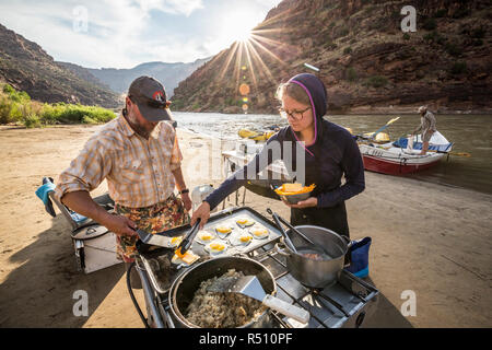 Due guide rafting cucinare un pasto presso il camp mentre su un Green River Rafting Trip Â desolazione/GrayÂ Canyon sezione, Utah, Stati Uniti d'America Foto Stock