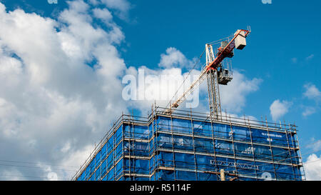 Un gruppo di lavoro di gru a torre sulla nuova unità home sito di costruzione con il bianco cumulus nubi in un cielo blu a Gosford, Nuovo Galles del Sud, Australia. Foto Stock