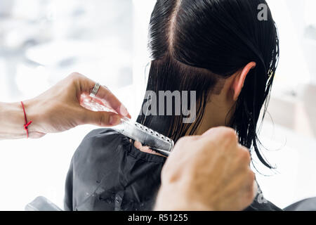 Parrucchiere taglia i capelli di una donna. Close-up. Foto Stock