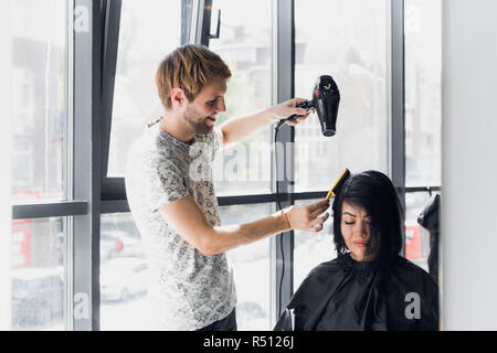 Donna sorridente getting haircut dal bel parrucchiere Foto Stock