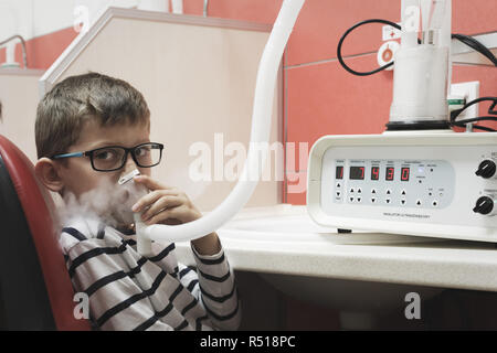 Ragazzo giovane prendendo l'inalazione delle vie respiratorie come l'asma immuno terapia in clinica Foto Stock