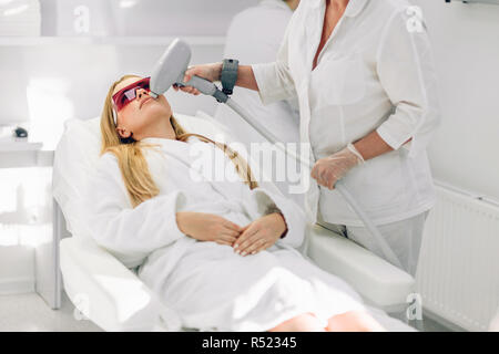 Donna getting laser e la faccia di ultrasuoni nel trattamento medico del centro termale Foto Stock