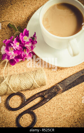 Fiori, forbici e iuta accanto alla tazza di caffè. Foto Stock