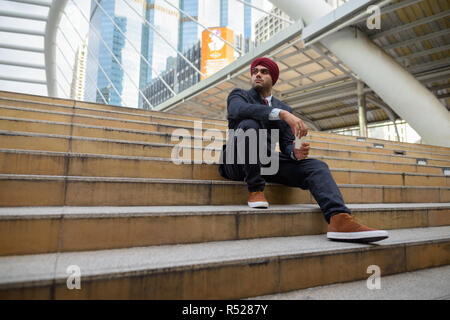 Commerciante indiano seduti all'aperto in città mentre pensando Foto Stock