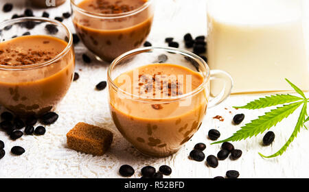 Tazze di caffè con la marijuana e fagioli arrosto su un tavolo Foto Stock