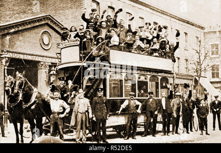 Staff,passeggeri, equipaggio di manutenzione e i passanti con uno degli ultimi (eventualmente l'ultimo) Coppia a cavallo a cavallo il tram / omnibuses in servizio al di fuori del London Regno del trasporto tranviario depot. È servito il Kew Gardens e nuovi giardini percorso. Foto Stock