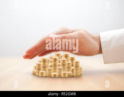 Pila di monete d'oro coperto dalla mano. Risparmi il concetto di protezione Foto Stock