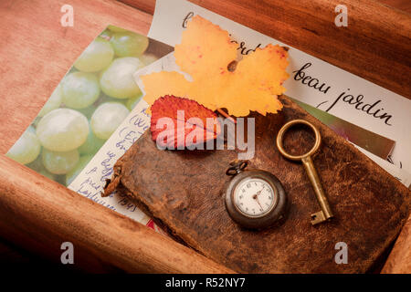 La nostalgia. Un vintage orologio da tasca, una chiave, foglie di autunno e la vecchia lettere e carte in una scatola di legno Foto Stock