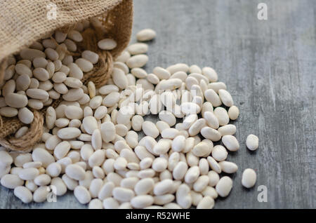 Fagioli nel sacco di tela su sfondo di legno Foto Stock