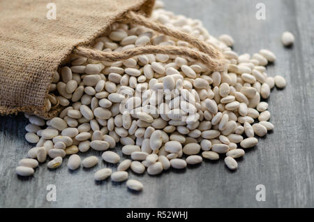 Fagioli nel sacco di tela su sfondo di legno Foto Stock