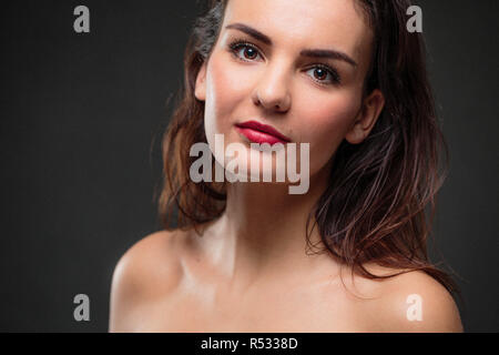 Ritratto di un sorridente giovane donna caucasica contro uno sfondo scuro - irradiando la fiducia e la femminilità (SHALLOW DOF dai toni di colore immagine) Foto Stock