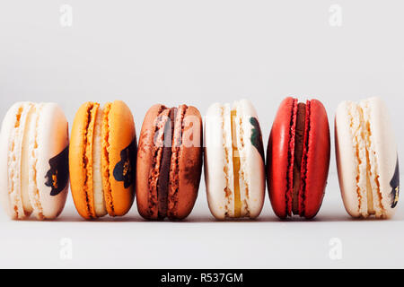 Elegante dessert francese con diversi ripieni. Set di macaron colorati decorate con colori di pasticceria e condimenti. Sfondo bianco. Foto Stock