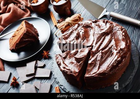 Guarnita con glassa al cioccolato servito su una piastra nera con vin brulé in tazze di terracotta accanto su tavoli in legno nero, vista da sopra Foto Stock