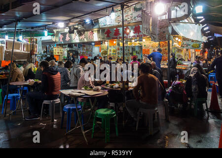 La gente del posto e i turisti cenare in un ristorante vicino il Mercato Notturno di Temple Street. Di Hong Kong, Kowloon, Yau Ma Tei, Gennaio 2018 Foto Stock