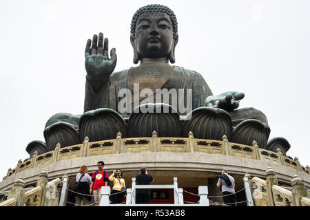 I turisti per scattare delle foto sotto la grande statua di Tian Tan Buddha. Hong Kong, l'Isola di Lantau, Gennaio 2018 Foto Stock