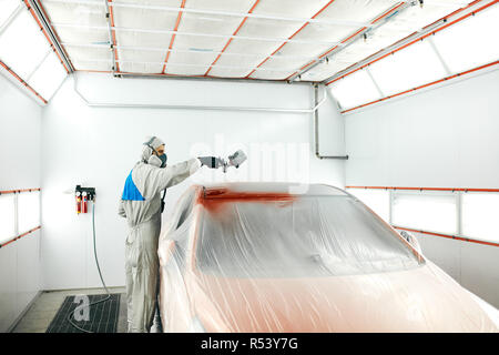 Auto pittore in indumenti da lavoro protettiva e respiratore verniciatura carrozzeria di auto in camera di verniciatura Foto Stock