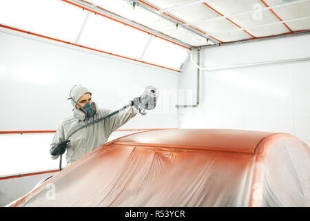 Auto pittore in indumenti da lavoro protettiva e respiratore verniciatura carrozzeria di auto in camera di verniciatura Foto Stock