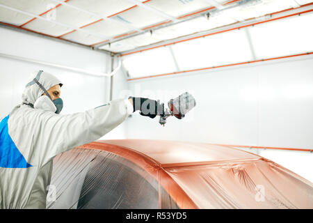 Auto pittore in indumenti da lavoro protettiva e respiratore verniciatura carrozzeria di auto in camera di verniciatura Foto Stock