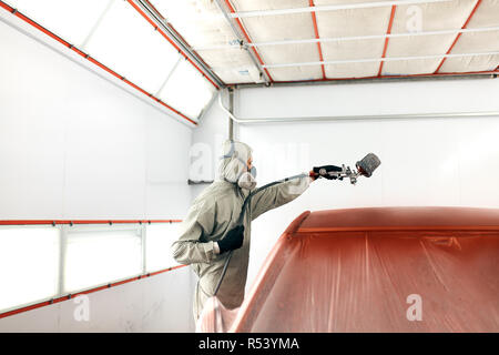 Auto pittore in indumenti da lavoro protettiva e respiratore verniciatura carrozzeria di auto in camera di verniciatura Foto Stock