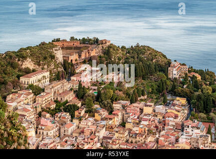 L'antico teatro greco al di sopra del villaggio di Taormina, provincia di Messina, Sicilia, Italia. Mare Mediterraneo sullo sfondo. Foto Stock