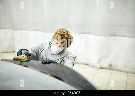 Mechanic grind auto parte per la verniciatura. Auto lavoro del corpo auto vernice di riparazione dopo incidente Foto Stock