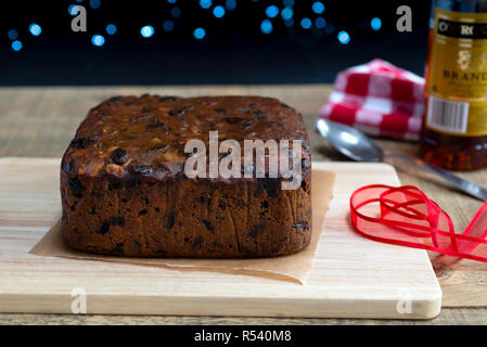 La preparazione di 'alimentazione' un frutto ricco di torta di Natale versando il brandy su di esso. Foto Stock