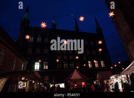 29 novembre 2018, Schleswig-Holstein, Lubecca: Molte persone visitano il Lübeck mercatino di Natale tra il municipio e la Marienkirche della città anseatica. Sul retro con quattro piccole torri di un lato del municipio può essere visto. Il primo Natale decorato mercati sono aperti in questi giorni. Altri seguiranno nei prossimi giorni. Foto: Rainer Jensen/dpa Foto Stock