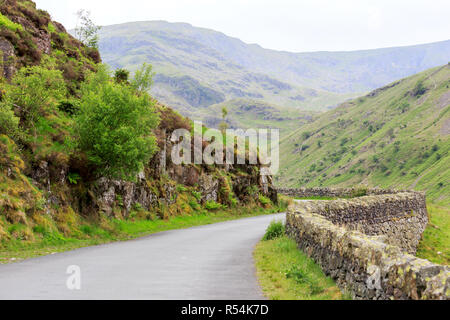 Una strada fiancheggiata con un muro di pietra nelle colline di pennini Foto Stock