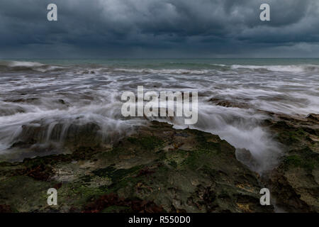 Una lunga esposizione delle onde che si infrangono sulle rocce durante un giorno di tempesta Foto Stock