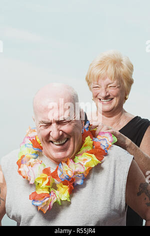 Donna mettendo una ghirlanda di fiori sul marito Foto Stock