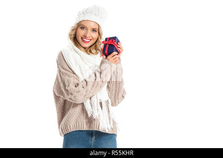 Bella sorridente giovane donna in abito invernale azienda piccolo dono isolato su bianco Foto Stock