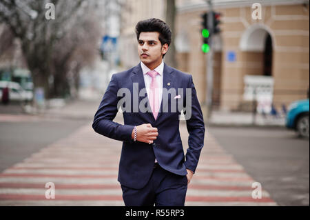 Elegante indiano uomo macho modello sulla tuta e cravatta rosa a piedi a croce pedonale. Foto Stock