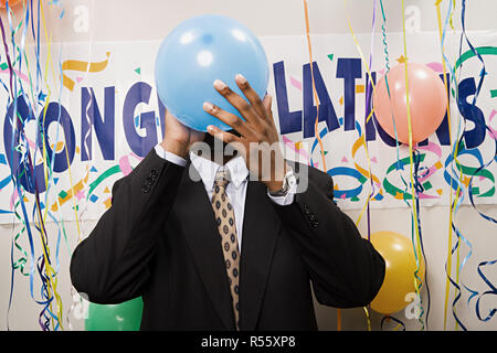 Imprenditore che soffia su un palloncino Foto Stock