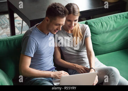 Emozionato l uomo e la donna seduta insieme e utilizzando computer portatile Foto Stock
