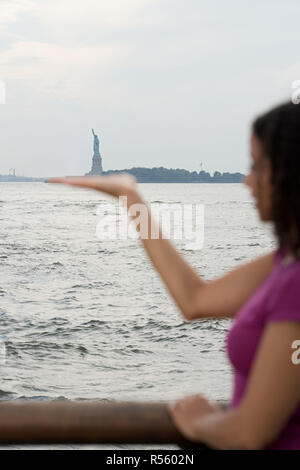 La donna finge di tenere la statua della libertà Foto Stock